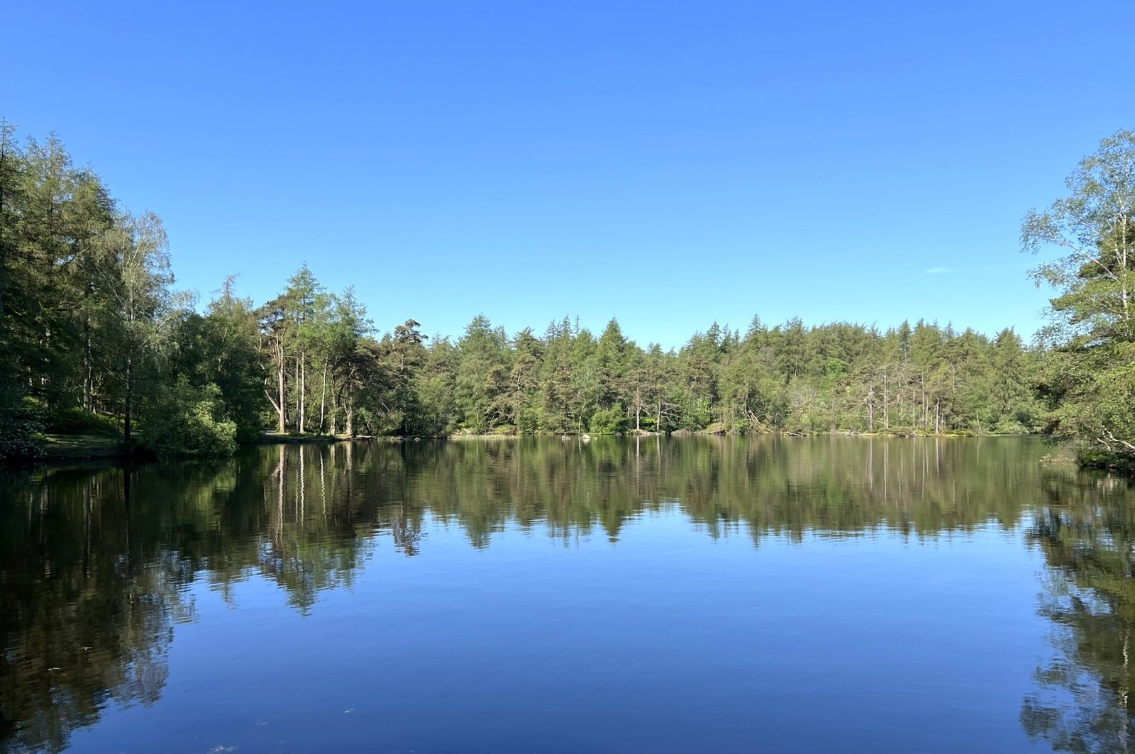 High Dam reflecting the trees that surround it. The sky is blue and clear.