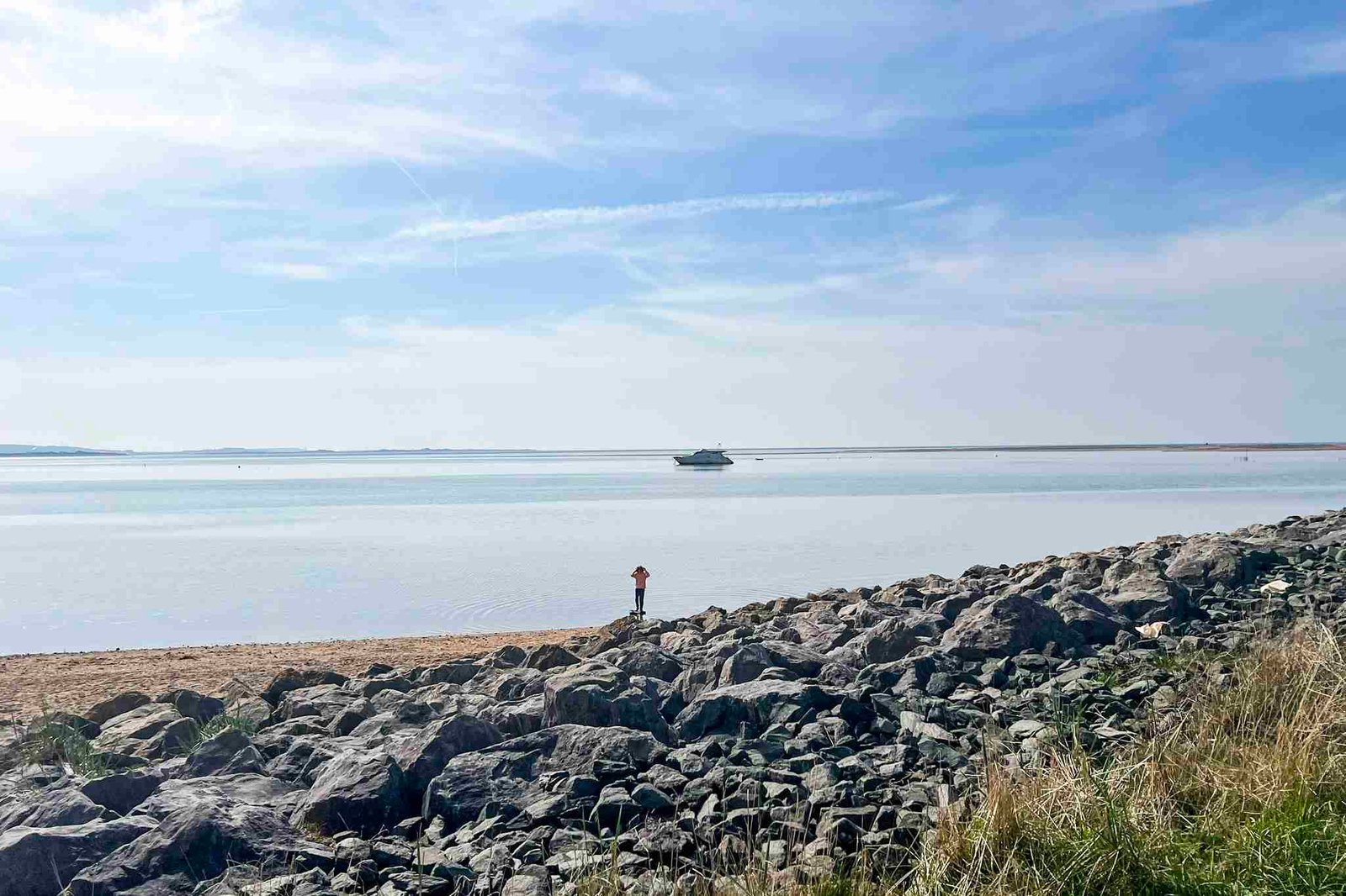 Haverigg beach and rocks. A boat is on the sea in the background.