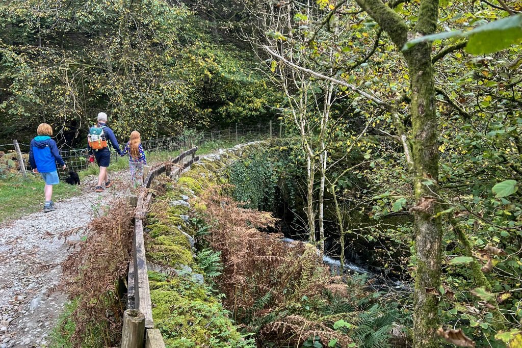 A dad and two children walk across Low Sweden Bridge, Ambleside.